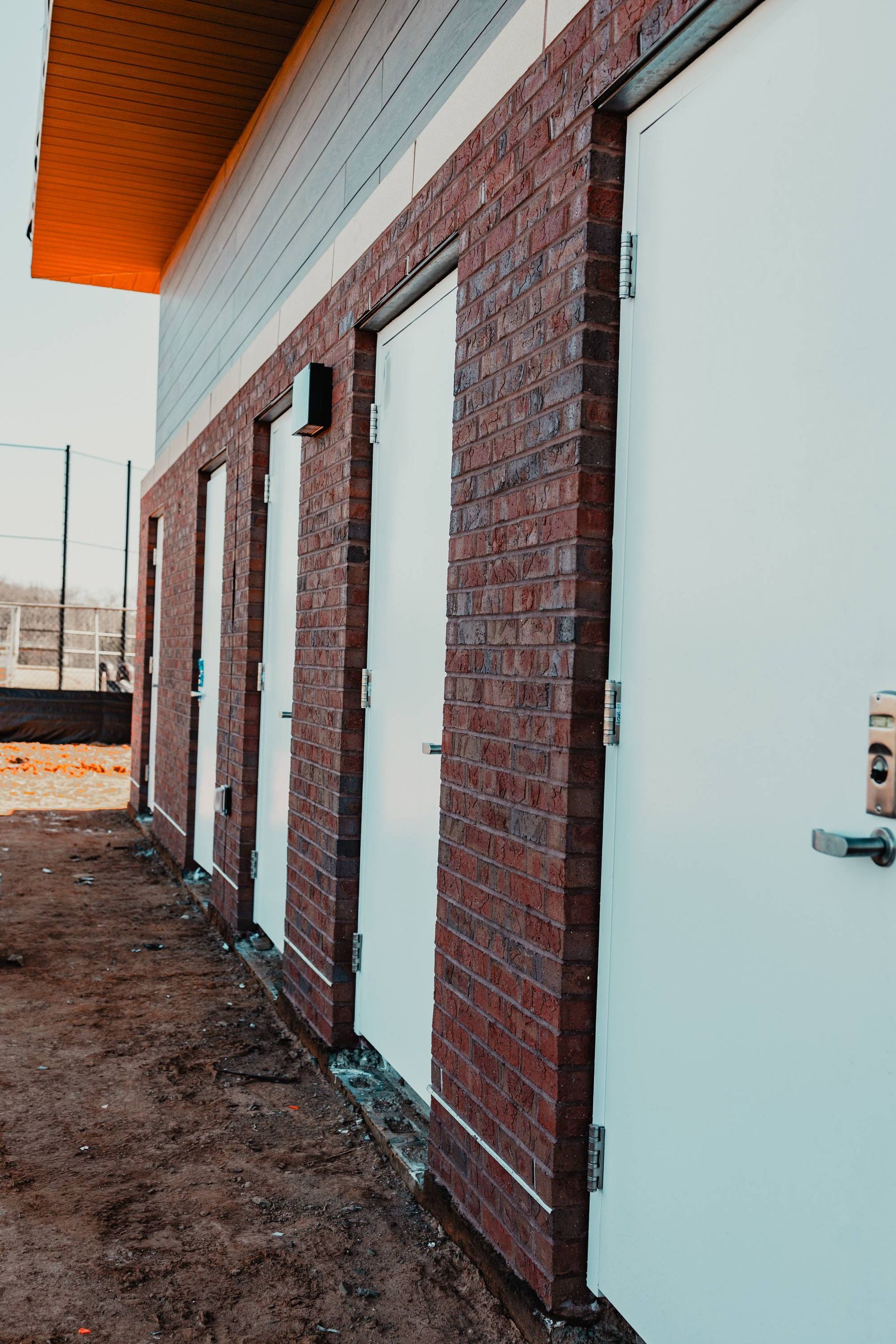 Red brick and white door exterior of a building; doors are in a row.