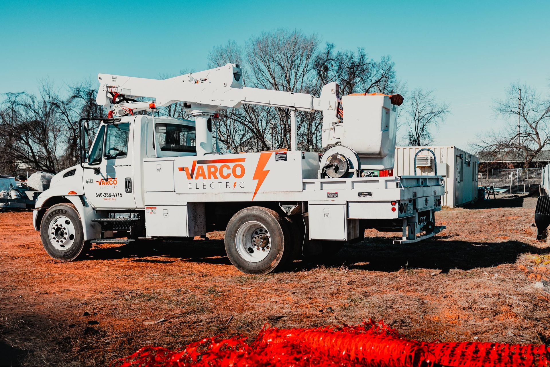 White Varco Electric truck with lift bucket in a field.