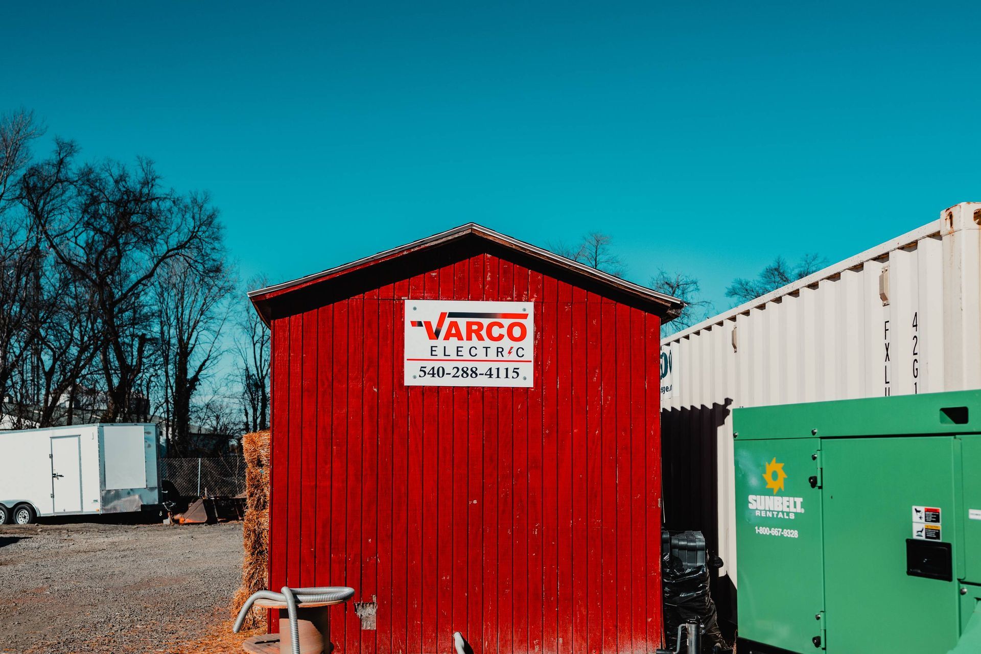 Red VARCO Electric building, white trailer, green generator, bright blue sky.