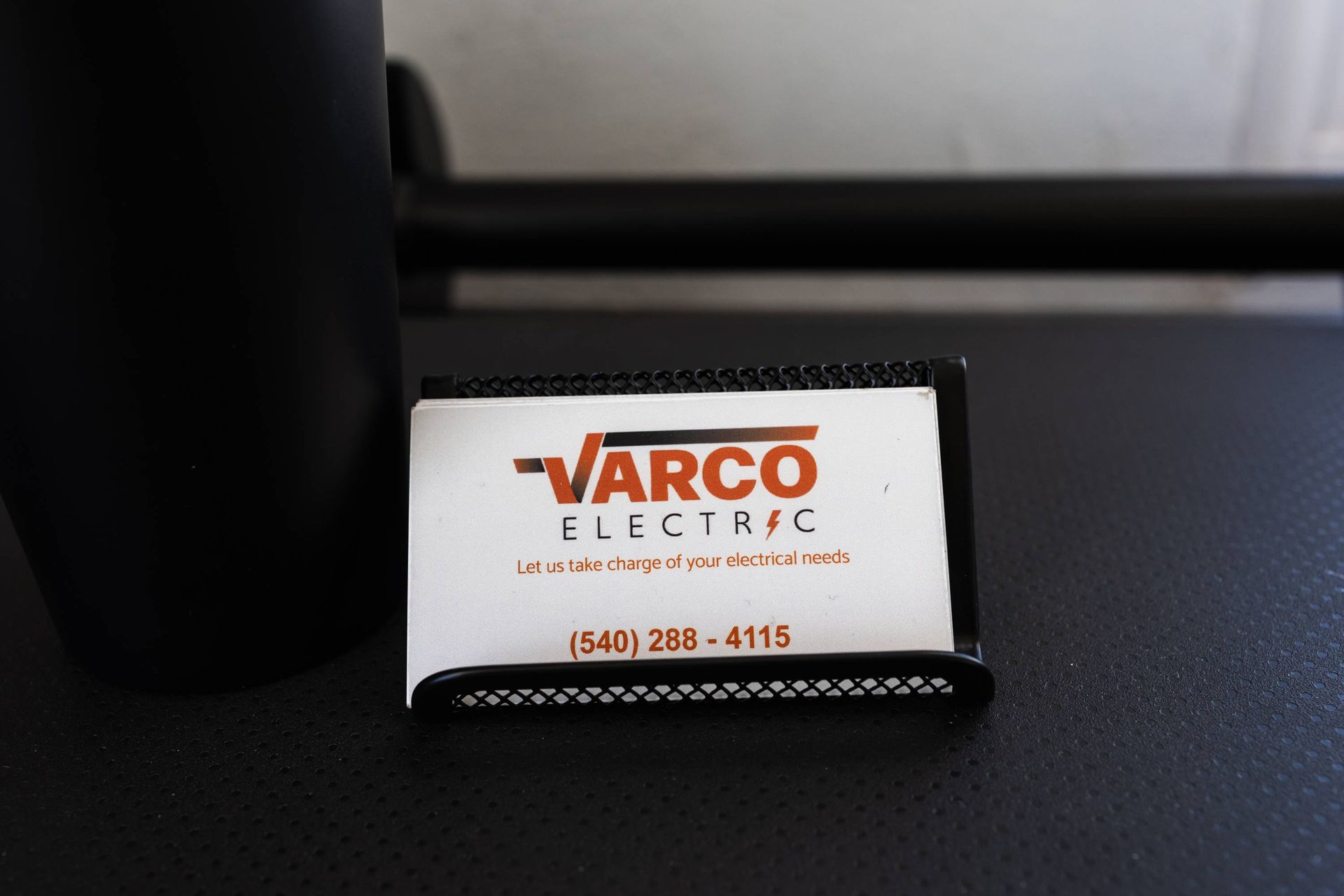 Business card for Varco Electric in a holder, with a phone number.