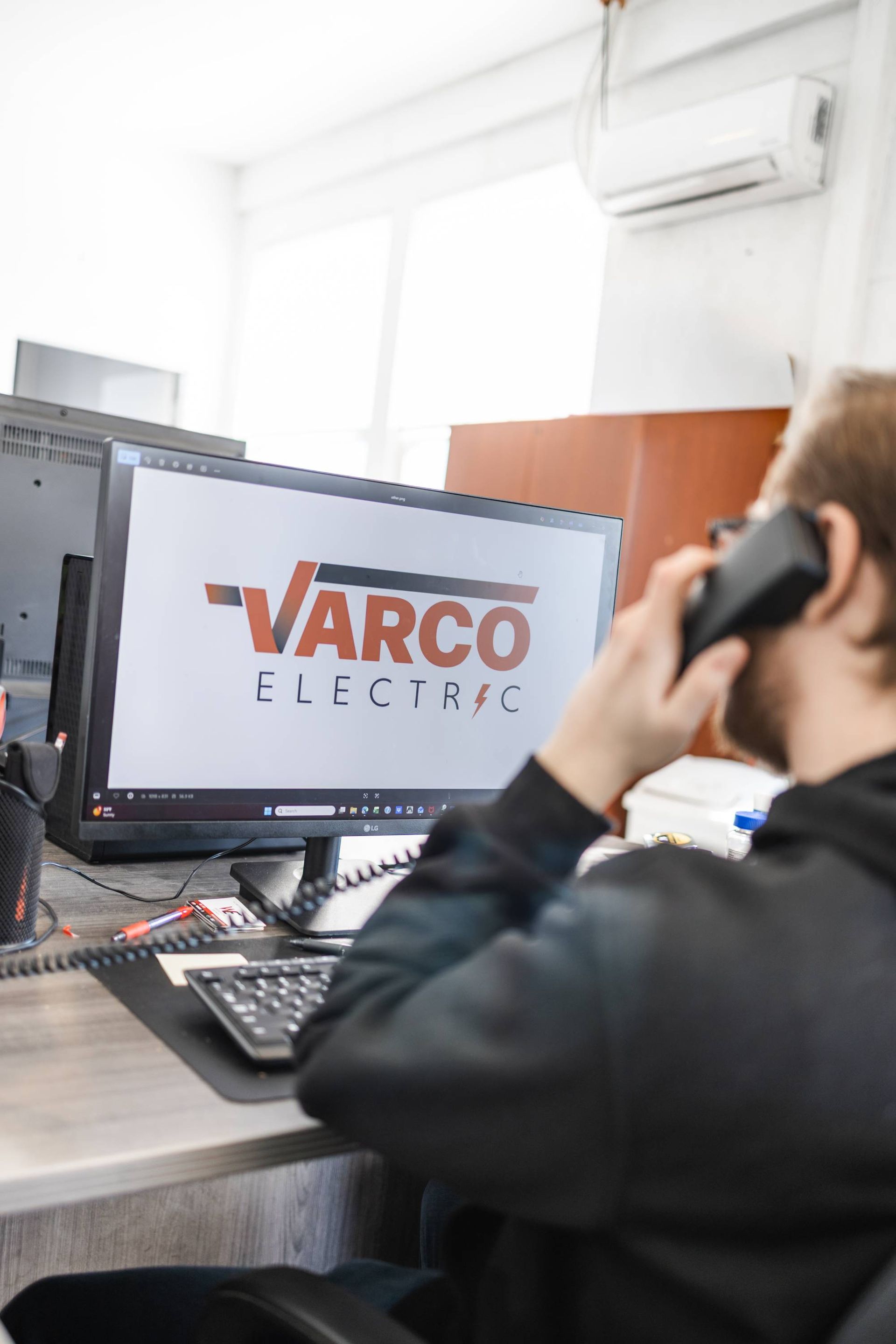 Person on phone in office; computer screen displays 