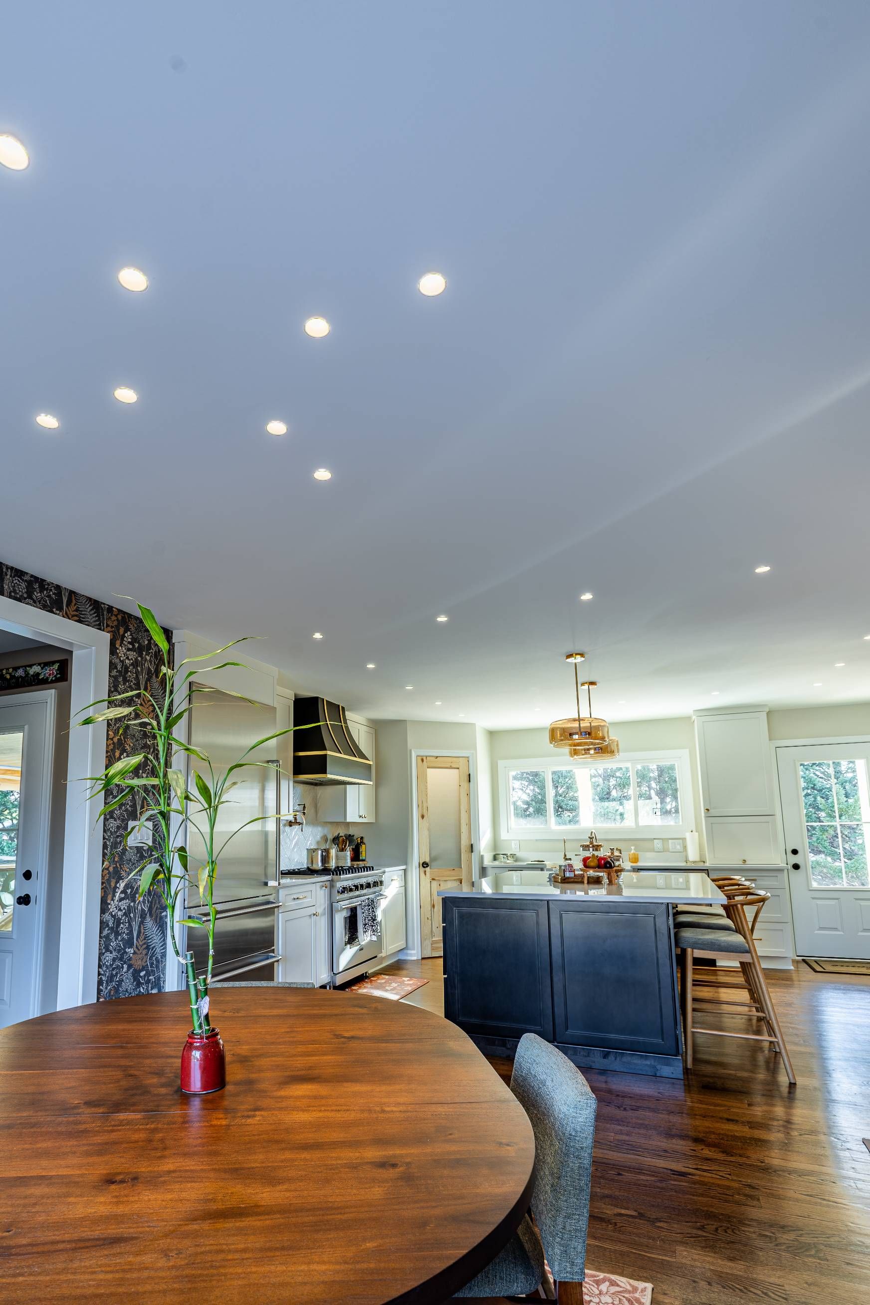 Spacious kitchen with a dark blue island, stainless steel appliances, and a wooden dining table.
