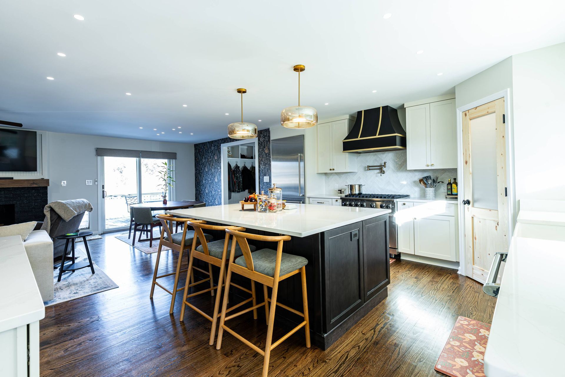 Spacious kitchen with a large island, stools, white cabinets, and stainless steel appliances.