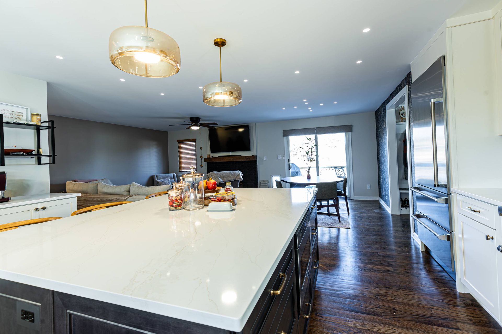 Spacious kitchen with large island and pendant lights, open to living and dining area with hardwood floors.