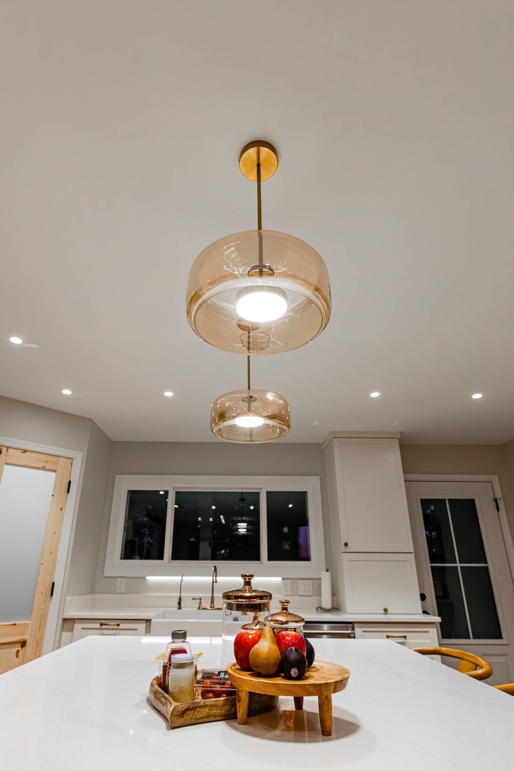 Three pendant lights hang over a kitchen island with a decorative tray.