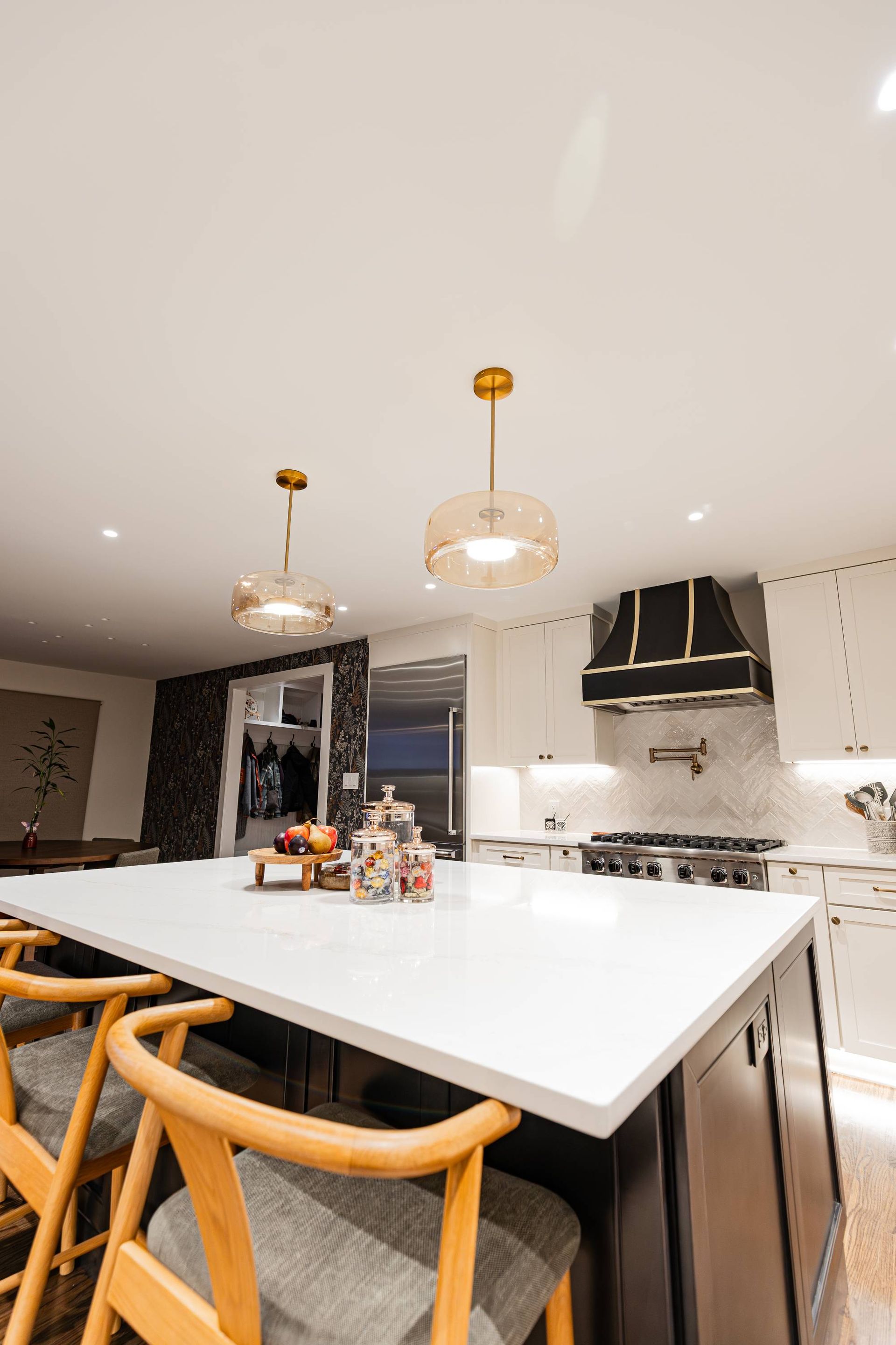 Modern kitchen with a white countertop island, gold pendant lights, and dark cabinets.