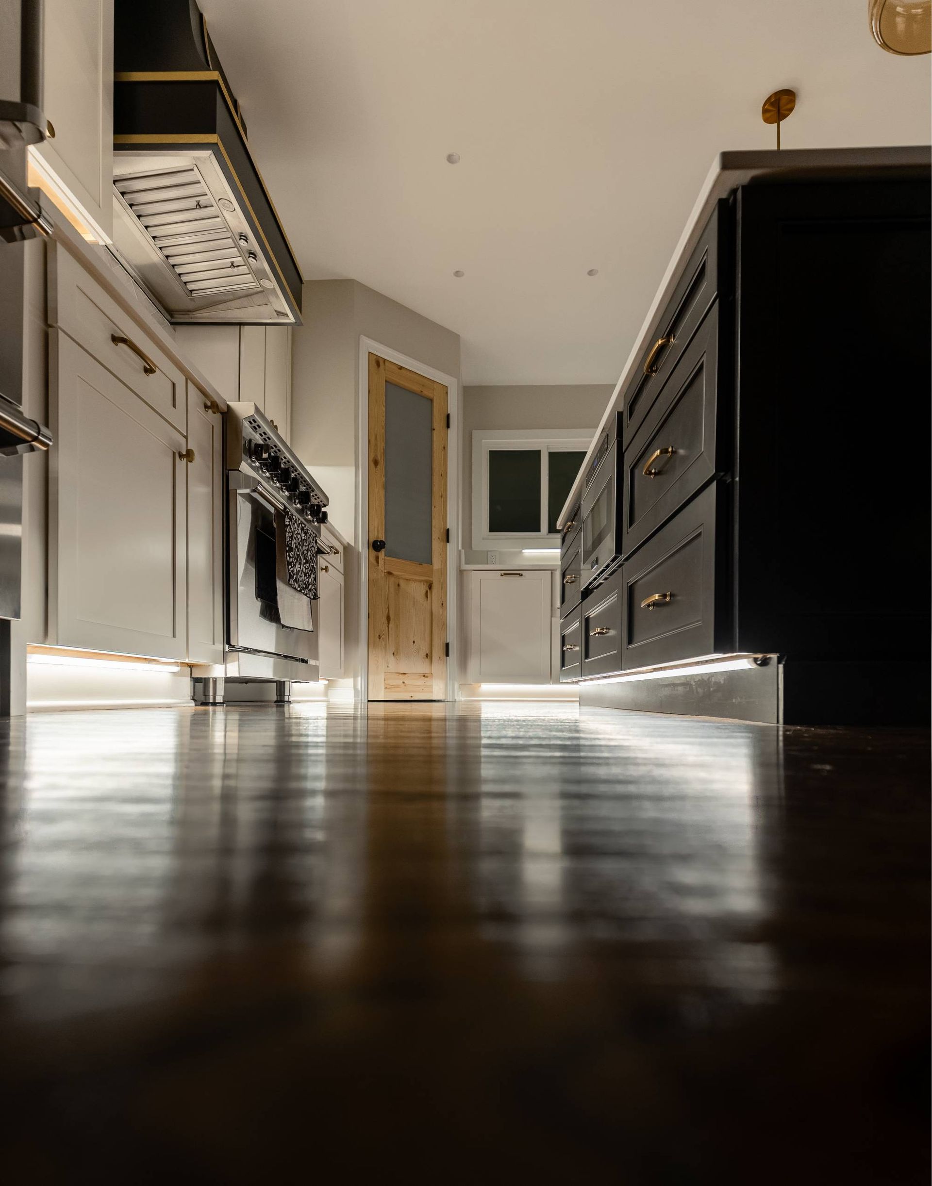 Low angle view of a kitchen with light wood floors, white cabinets, and a dark island.