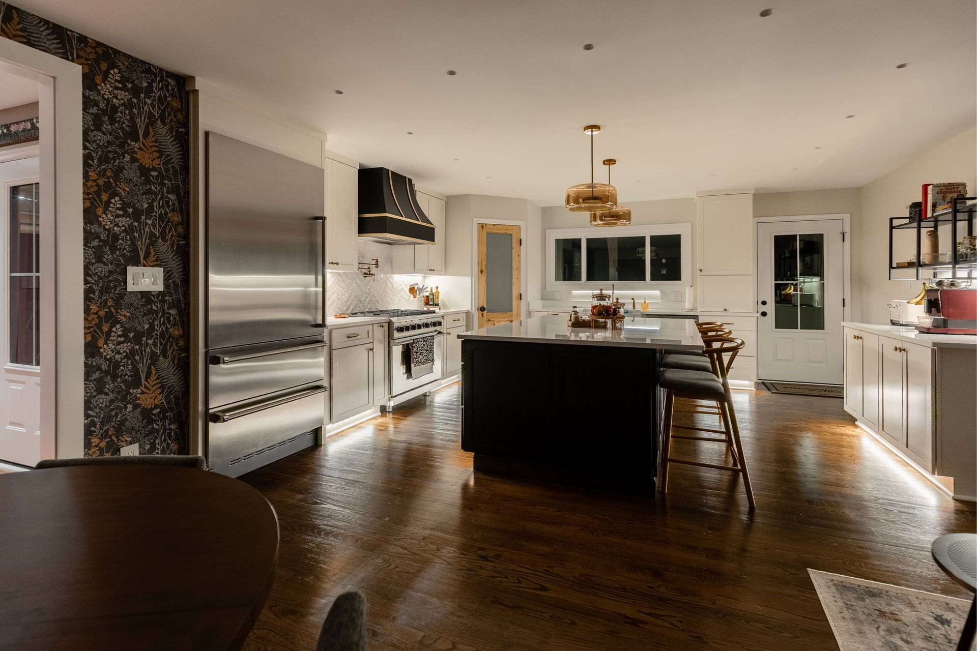 Modern kitchen with stainless steel appliances, dark island, and wood floors.