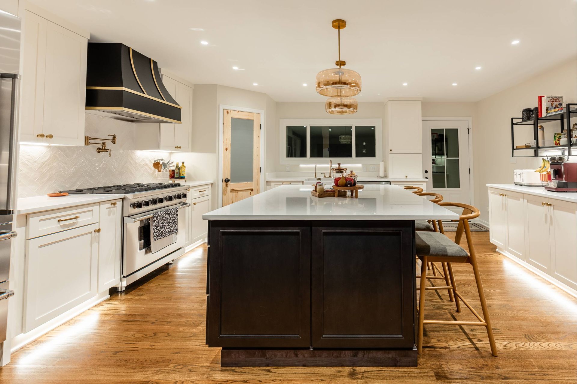 Modern kitchen with black and white cabinets, large island, and wood floors.