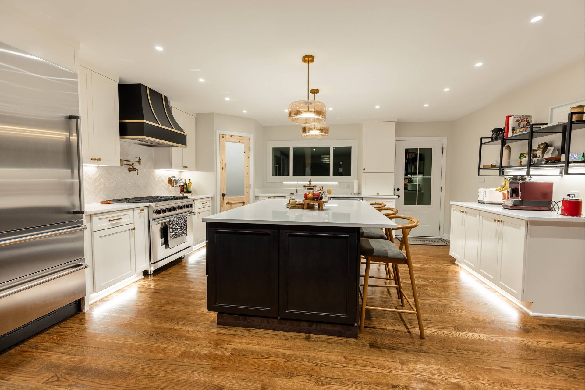 Modern kitchen with white cabinets, dark island, stainless steel appliances, and gold accents.