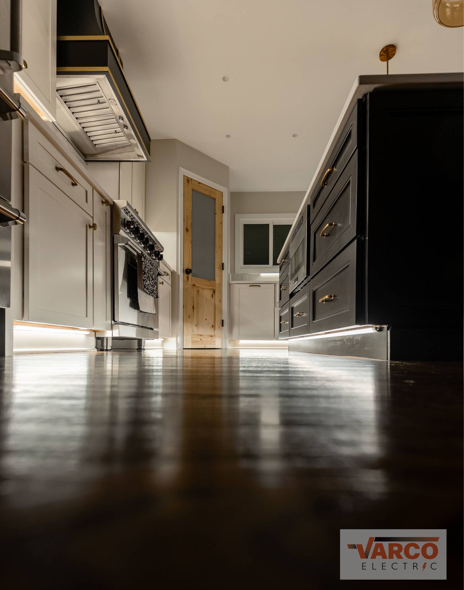 Kitchen with island and cabinets, hardwood floor, warm lighting.