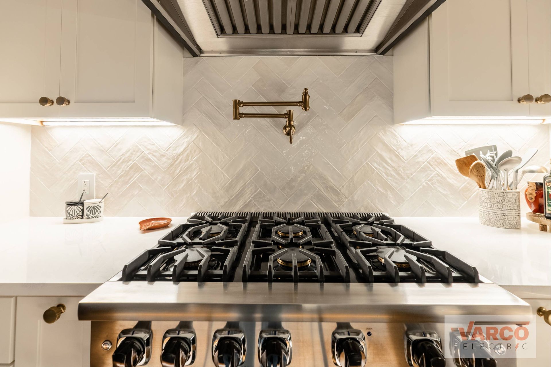 Kitchen stove with backsplash and pot filler, under cabinet lighting, white cabinets.