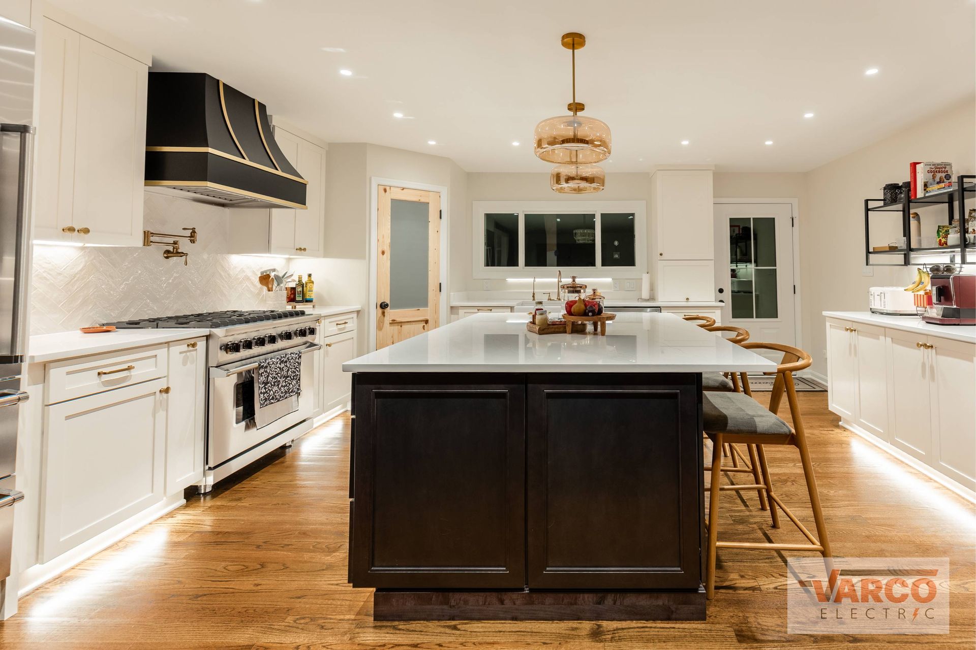 Modern kitchen with white cabinets, dark island, and a gold light fixture.