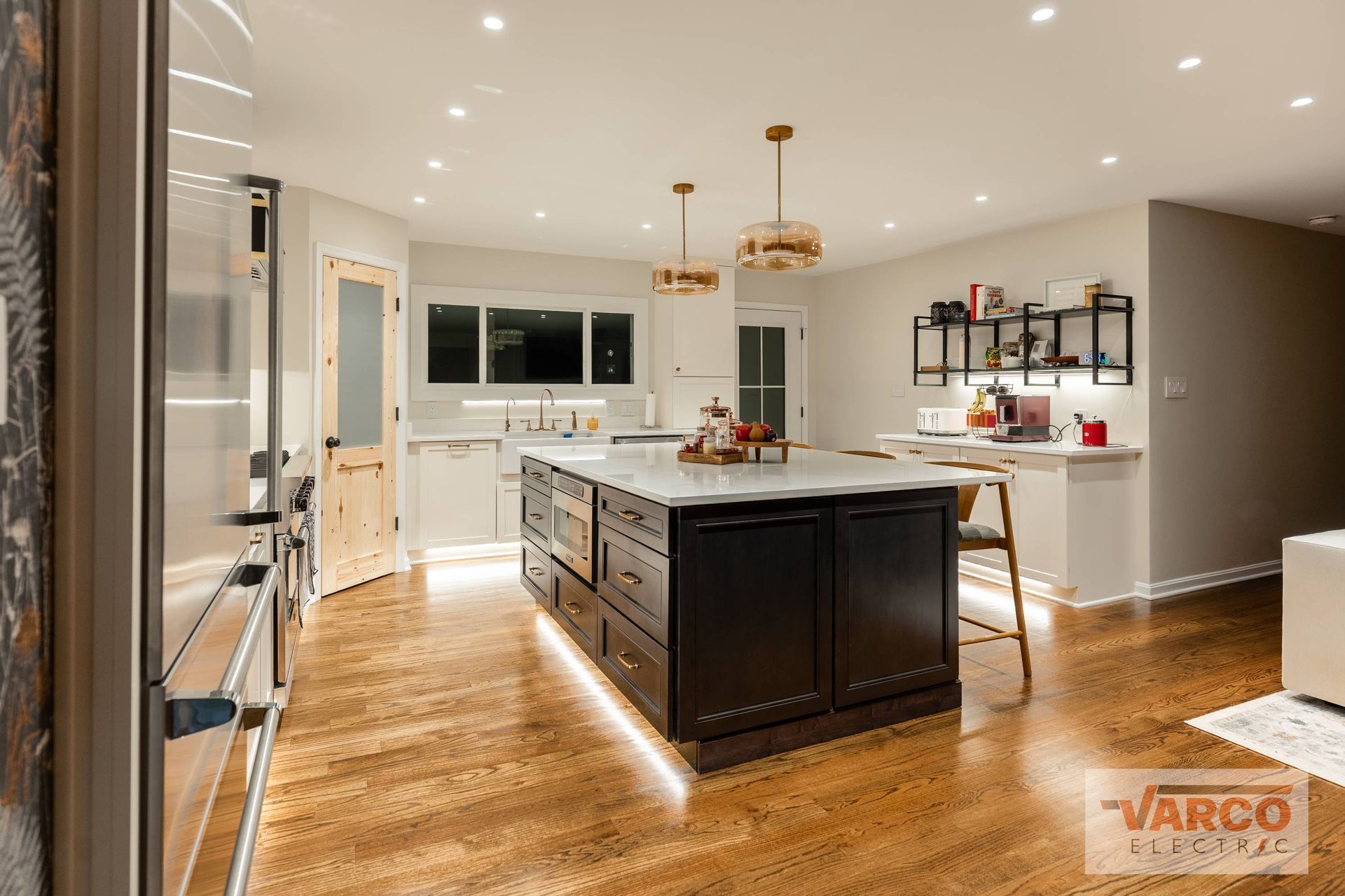 Modern kitchen with dark island and light wood floors, recessed lighting.