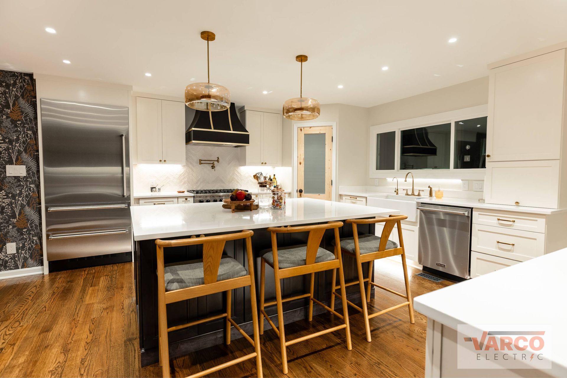 Modern kitchen with island, white cabinets, stainless steel appliances, and wood floors.