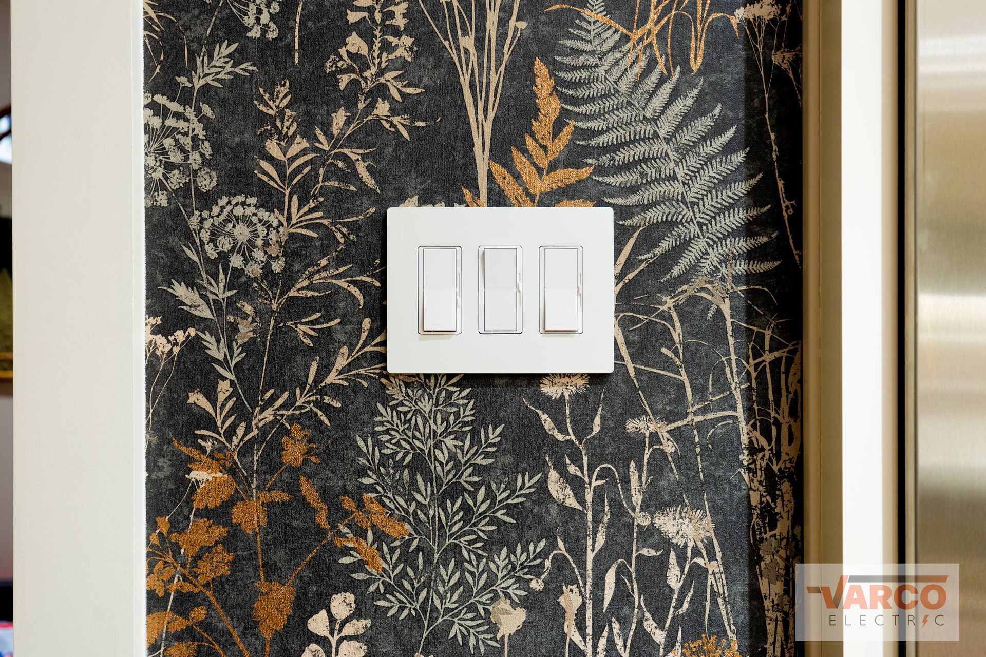 White light switches on wallpaper with a dark floral pattern.