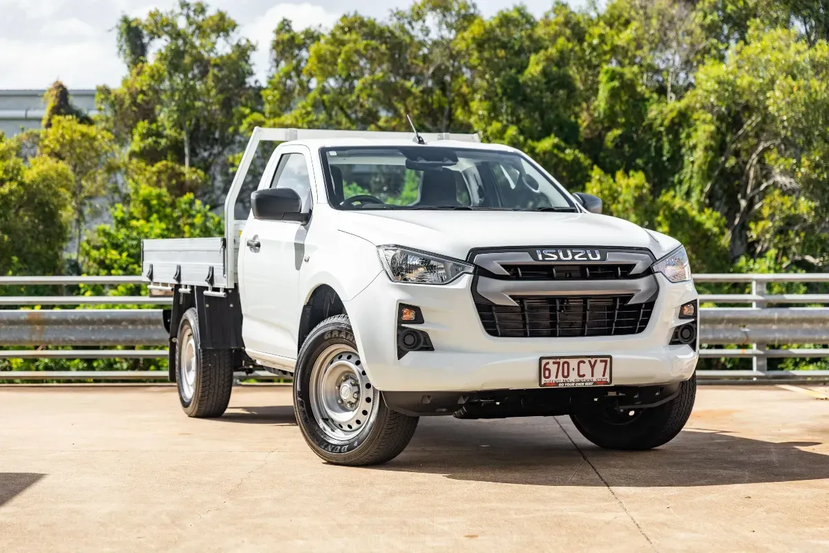 A white isuzu truck is parked on the side of the road.