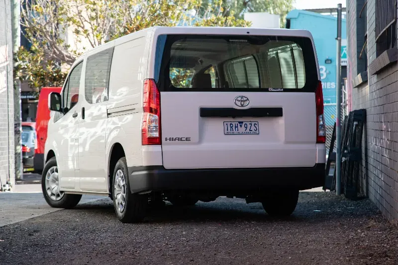 A white van is parked in a parking lot next to a building.