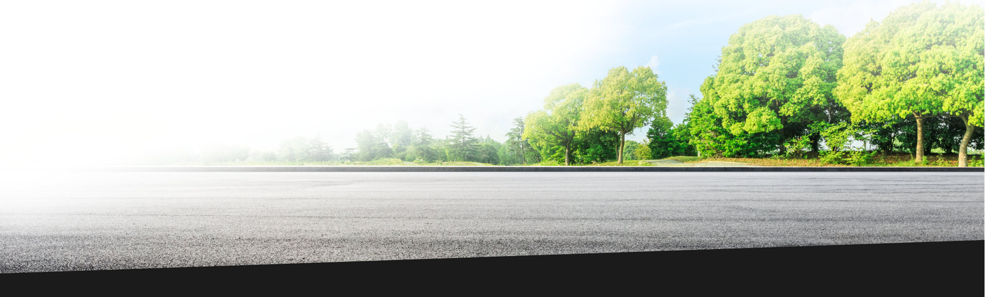 Asphalt road with green trees in the background under a blue sky. | Ashten's Total Auto Care
