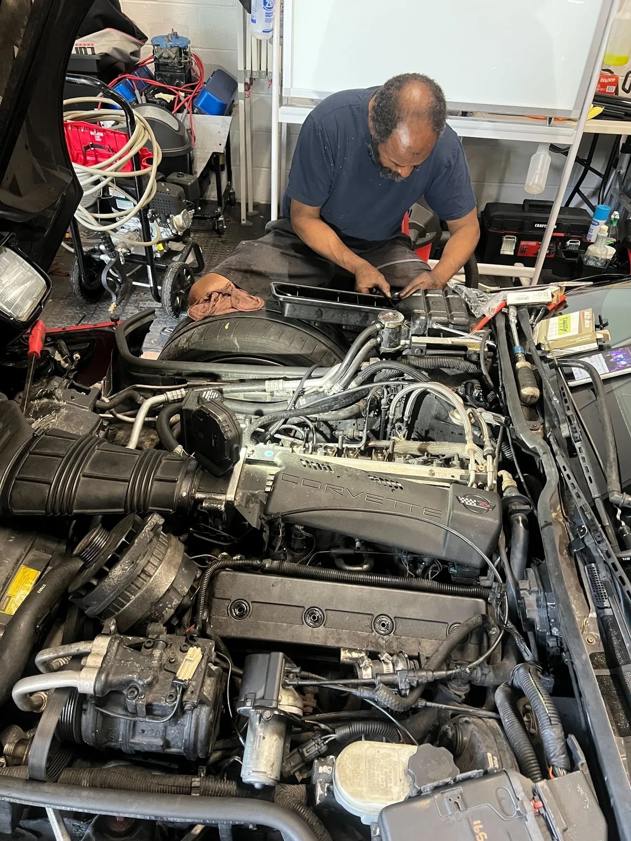 Man working on a car engine in a garage. | Ashten's Total Auto Care