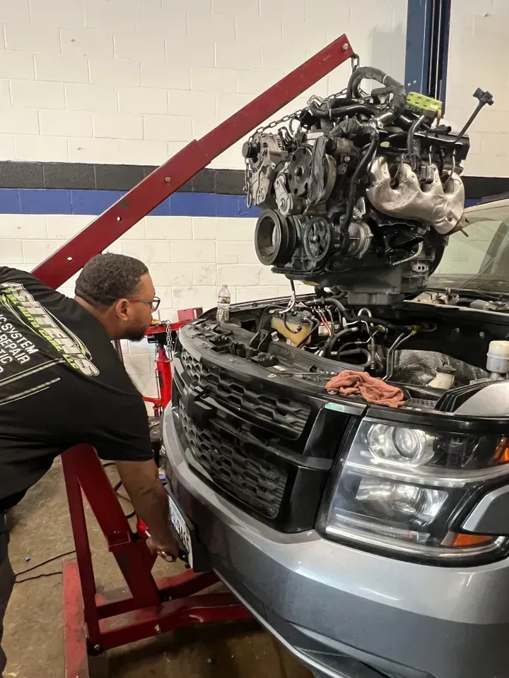 A mechanic removes a car engine with a hoist in a repair shop. | Ashten's Total Auto Care