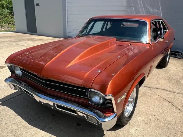 Orange classic car with hood scoop, chrome trim, parked outdoors. | Ashten's Total Auto Care