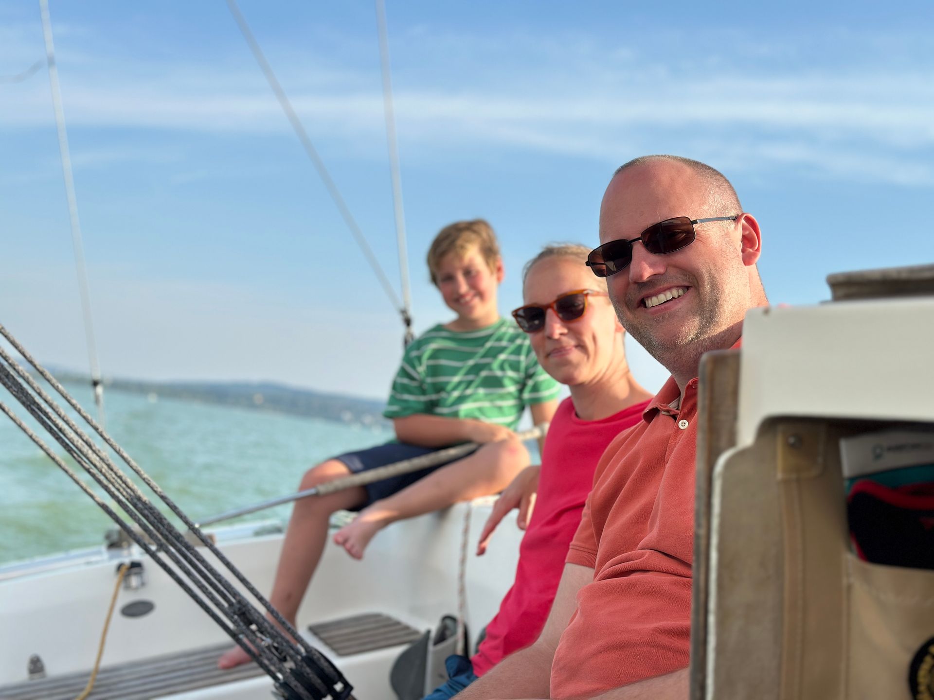 Family smiles on a sailboat on a sunny day.