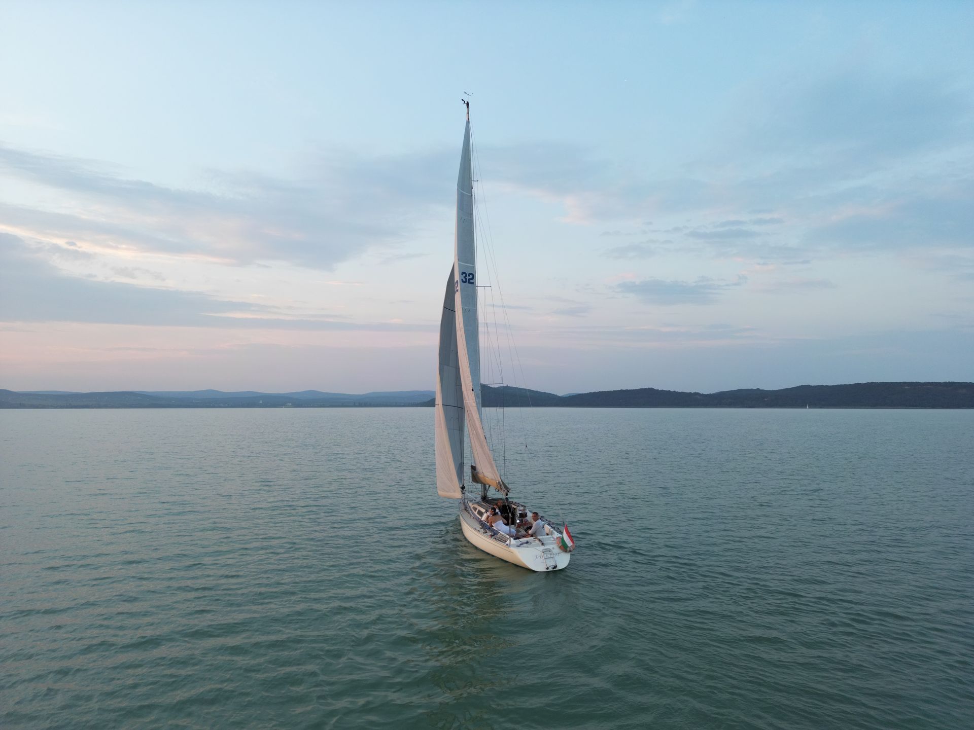 Sailboat sailing on calm water at dusk.