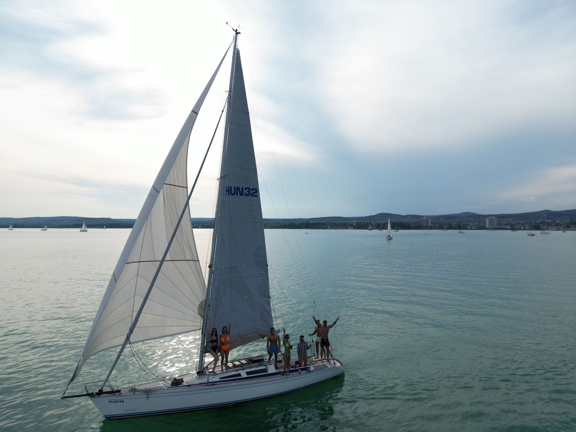 Sailboat with people sailing on a lake on a sunny day.