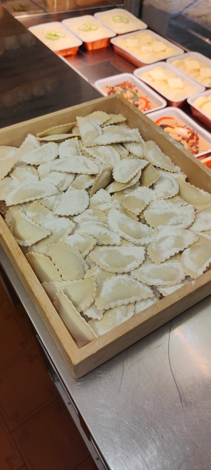 Sul bancone c'è un vassoio di legno pieno di ravioli.