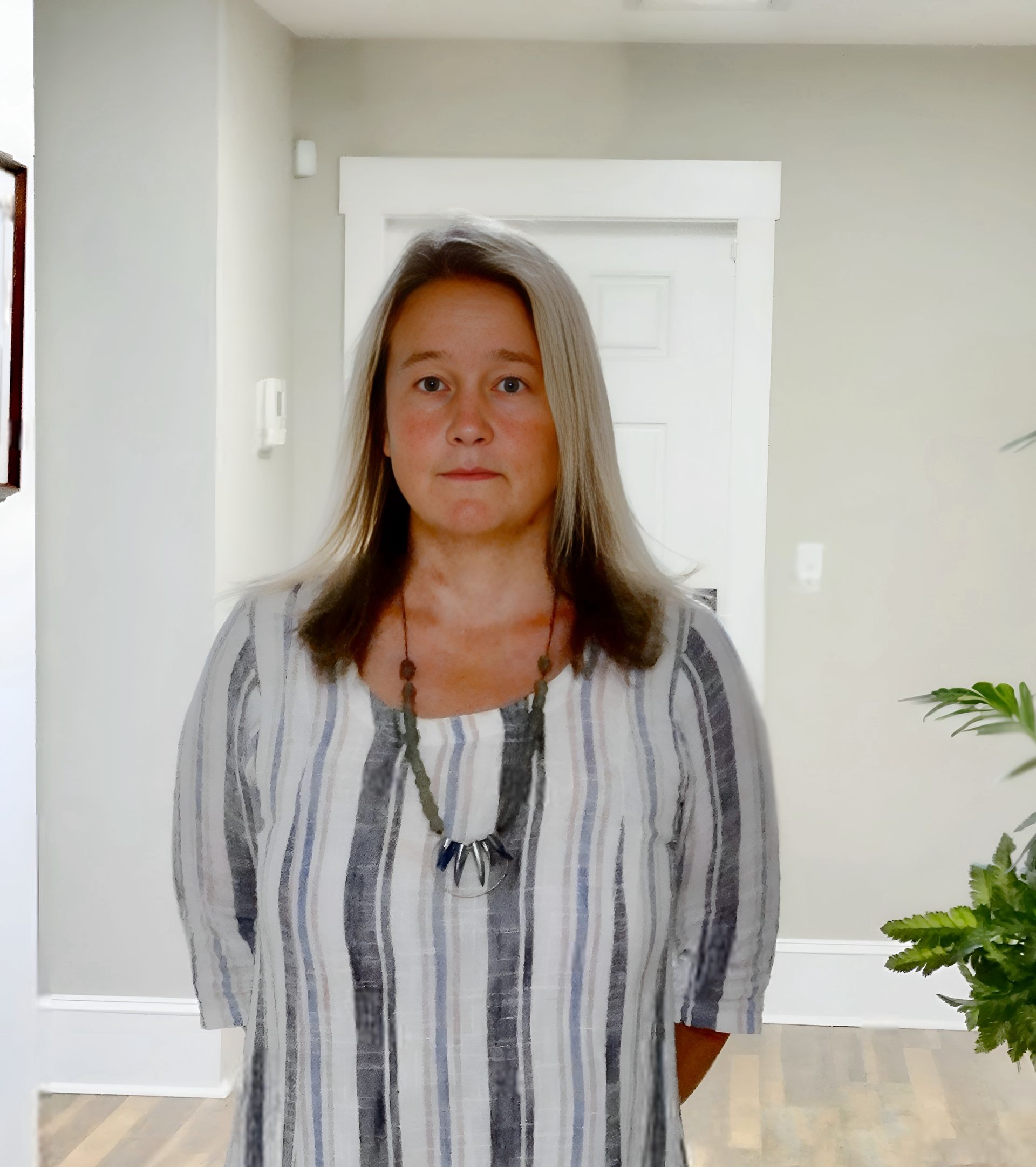 A woman wearing a black sweater and a pearl necklace is smiling for the camera.