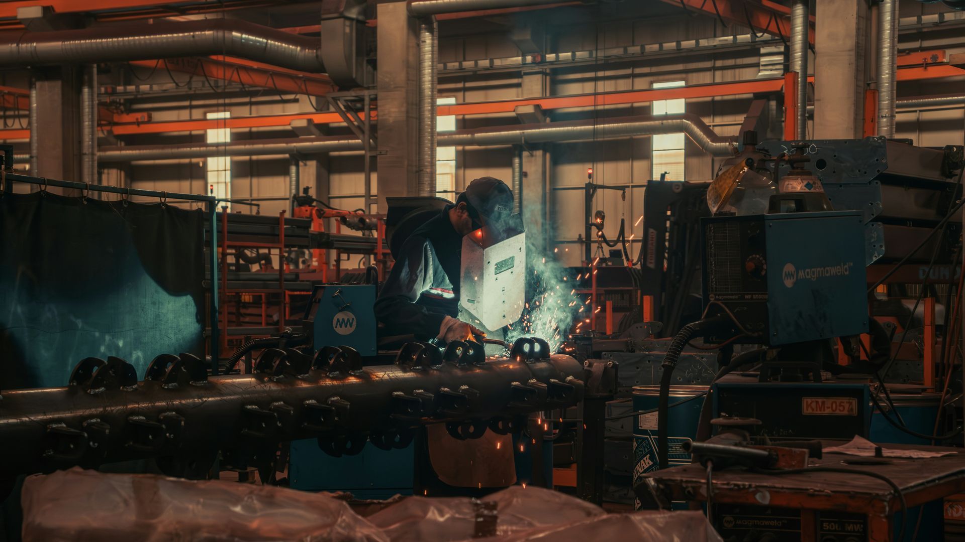 A man is welding a pipe in a factory.