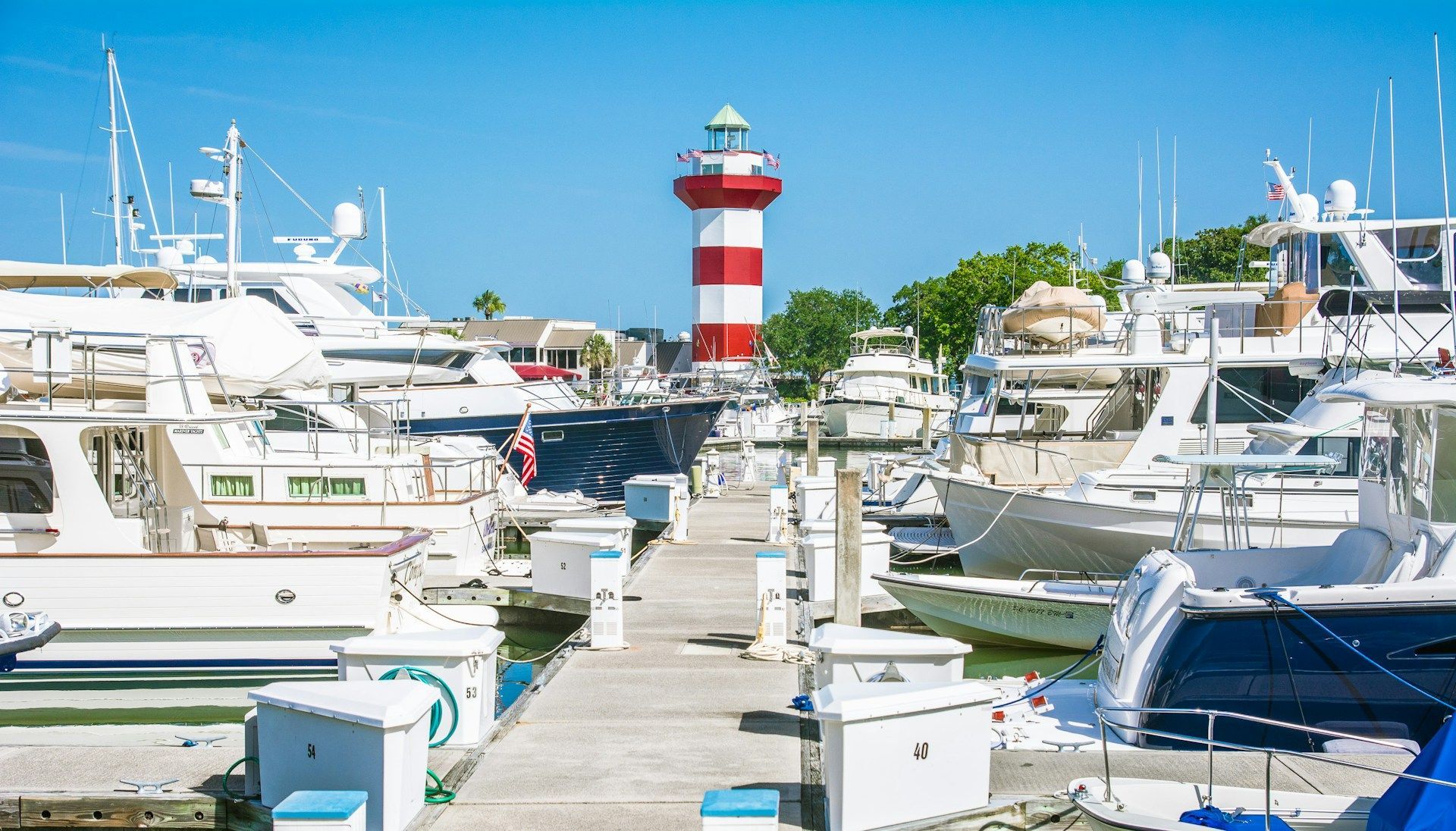 A marina filled with boats and a lighthouse in the background.