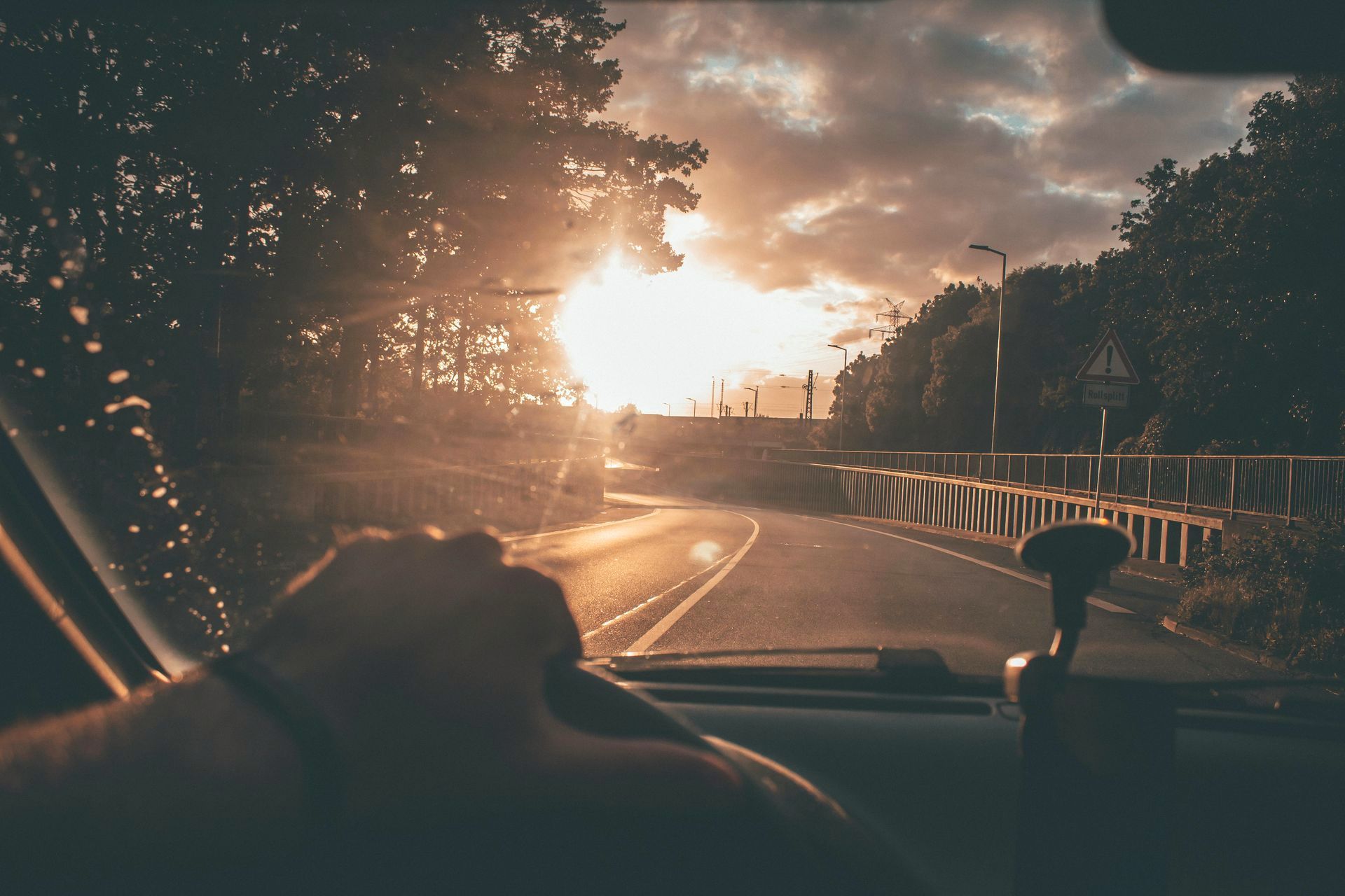 A person is driving a car down a road at sunset.