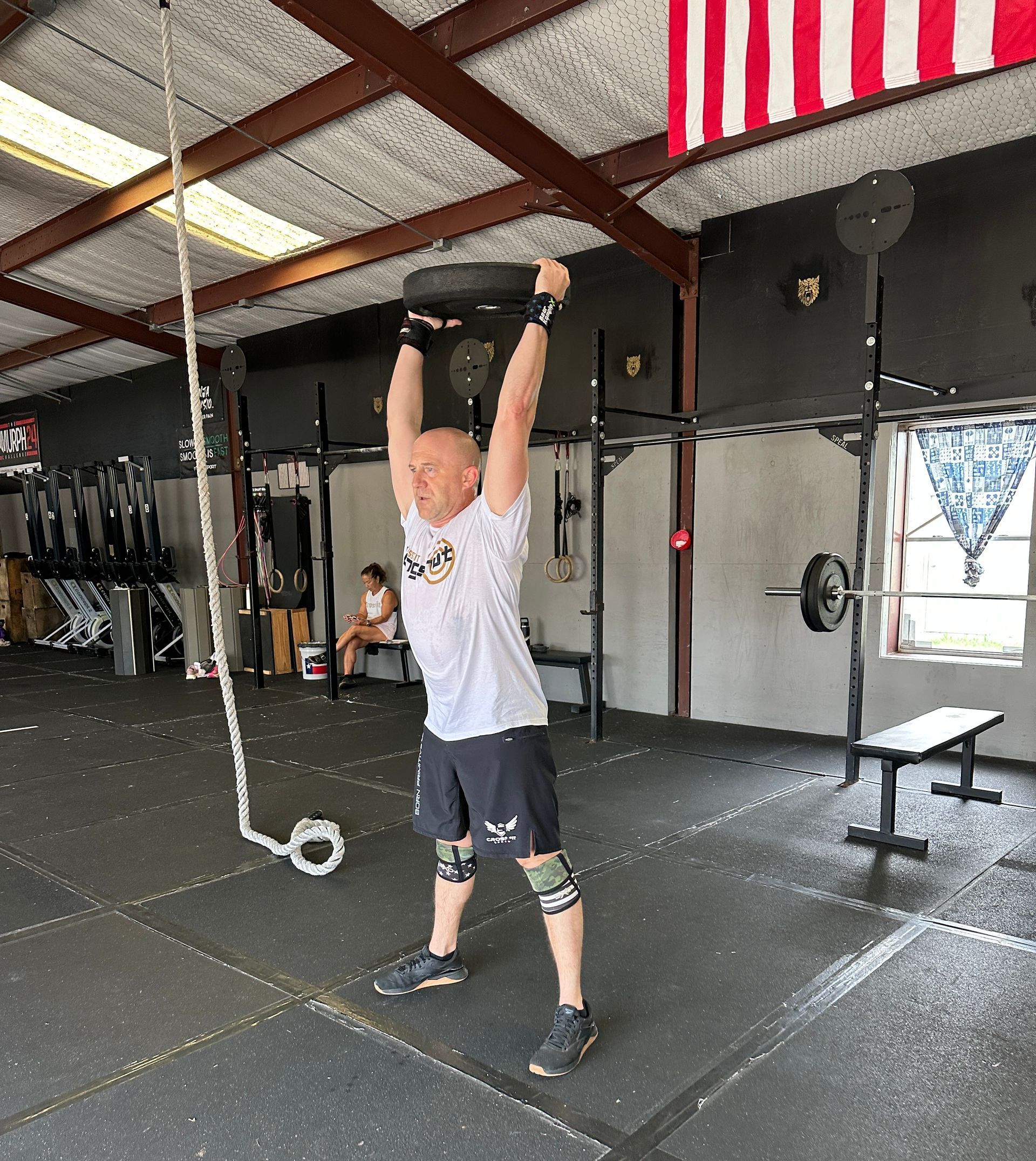 A man is lifting a barbell over his head in a gym.