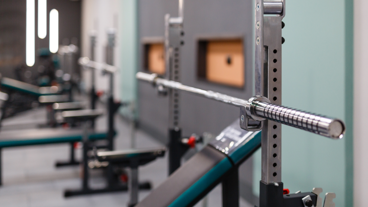 A barbell is sitting on a rack in a gym.