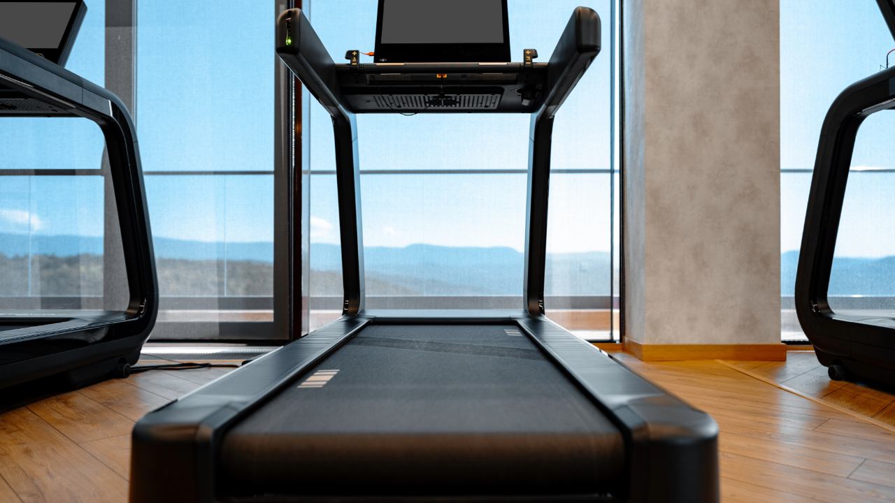 A treadmill is sitting in a gym next to a window.