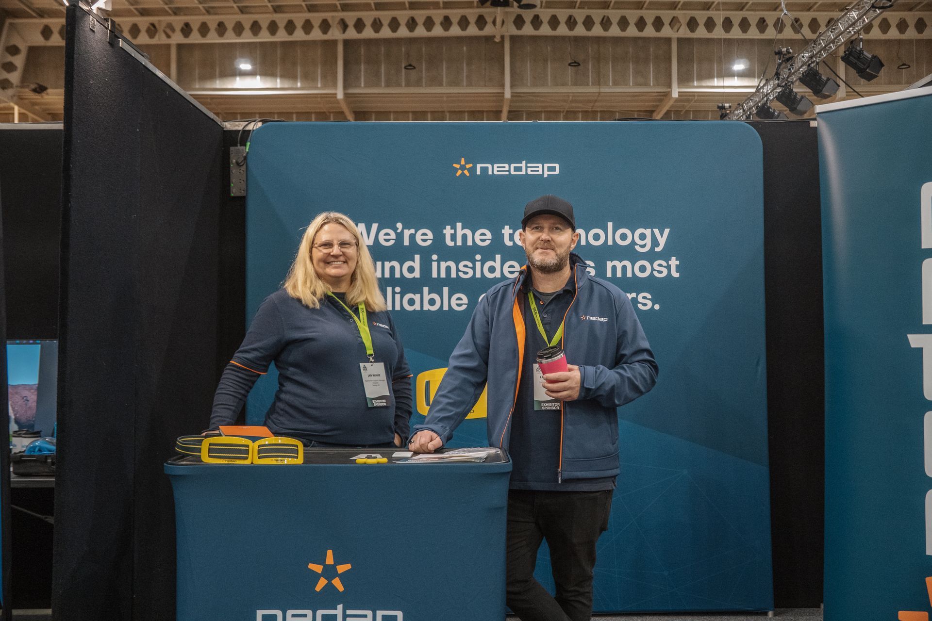 Two people stand behind a trade show booth with 