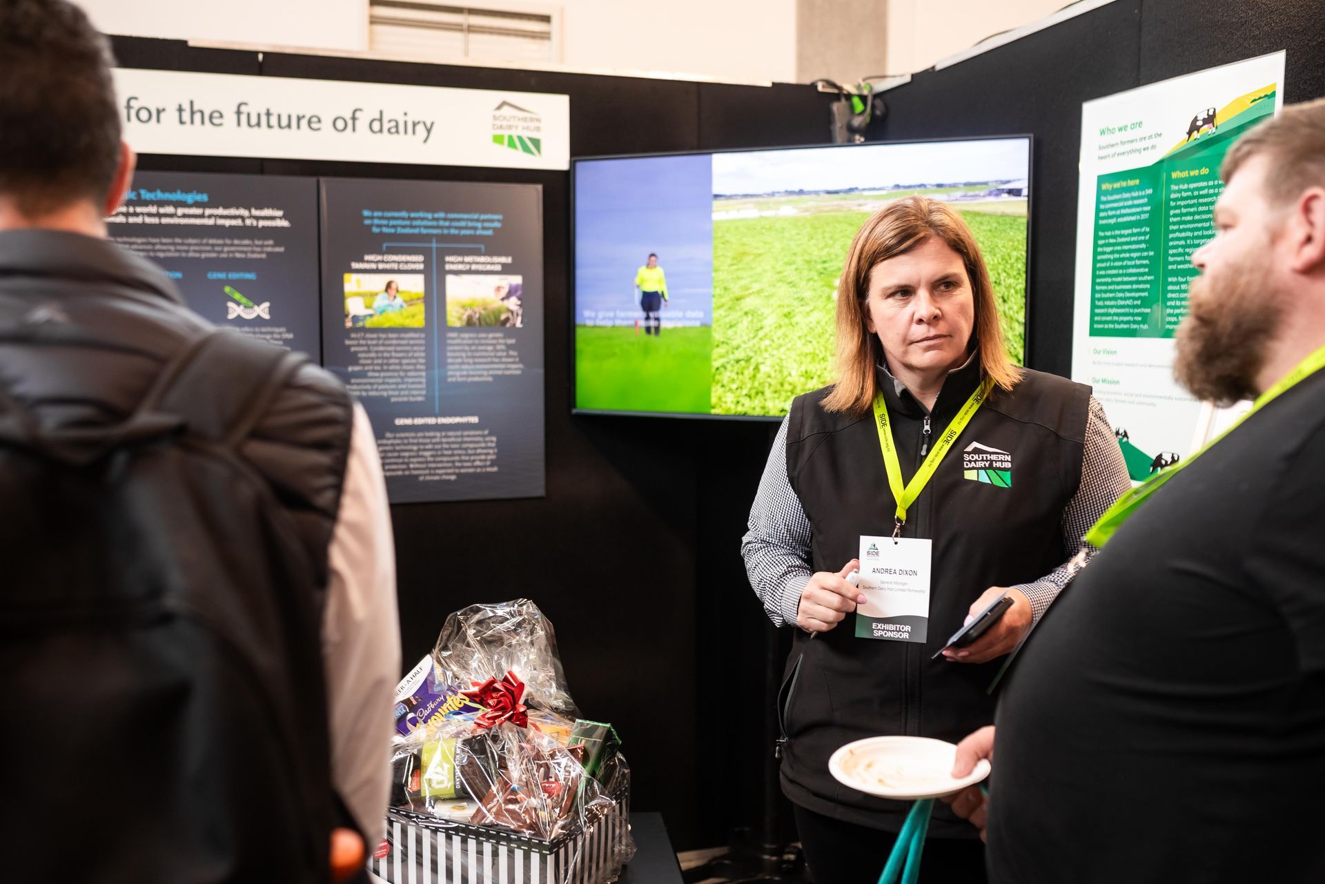 Woman at a dairy future display booth; talking to attendees. 
