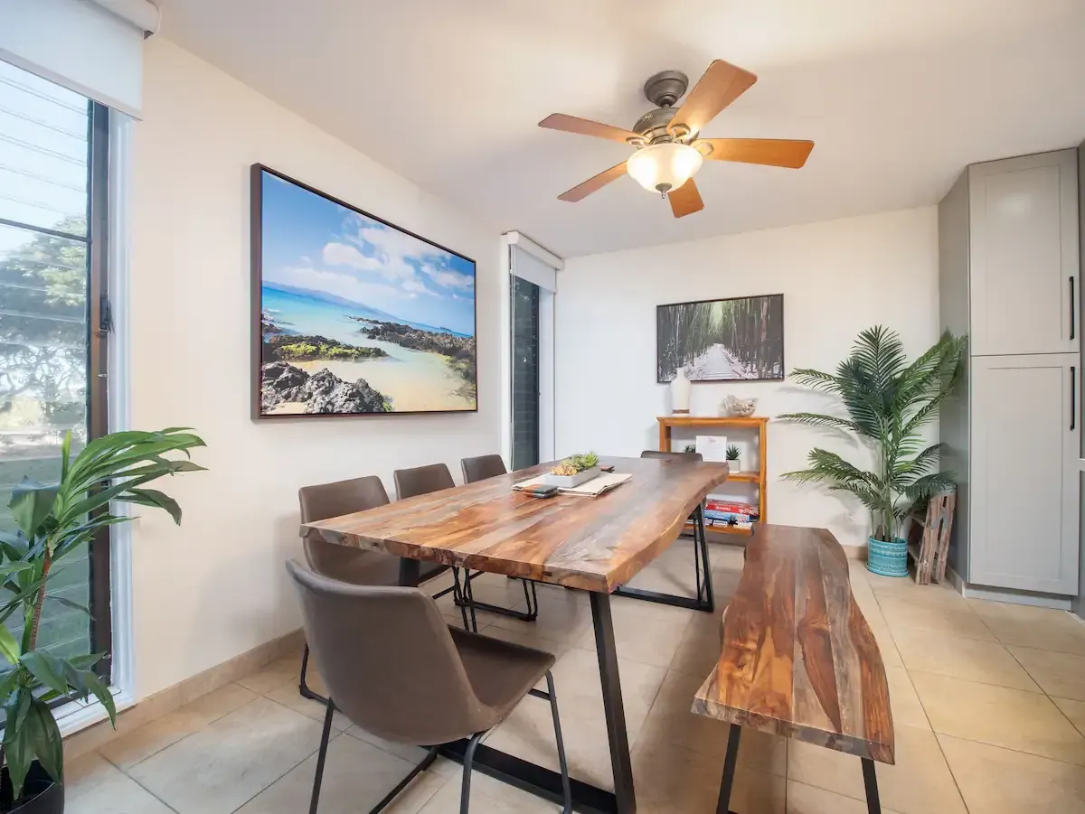 A dining room with a wooden table and chairs and a ceiling fan.