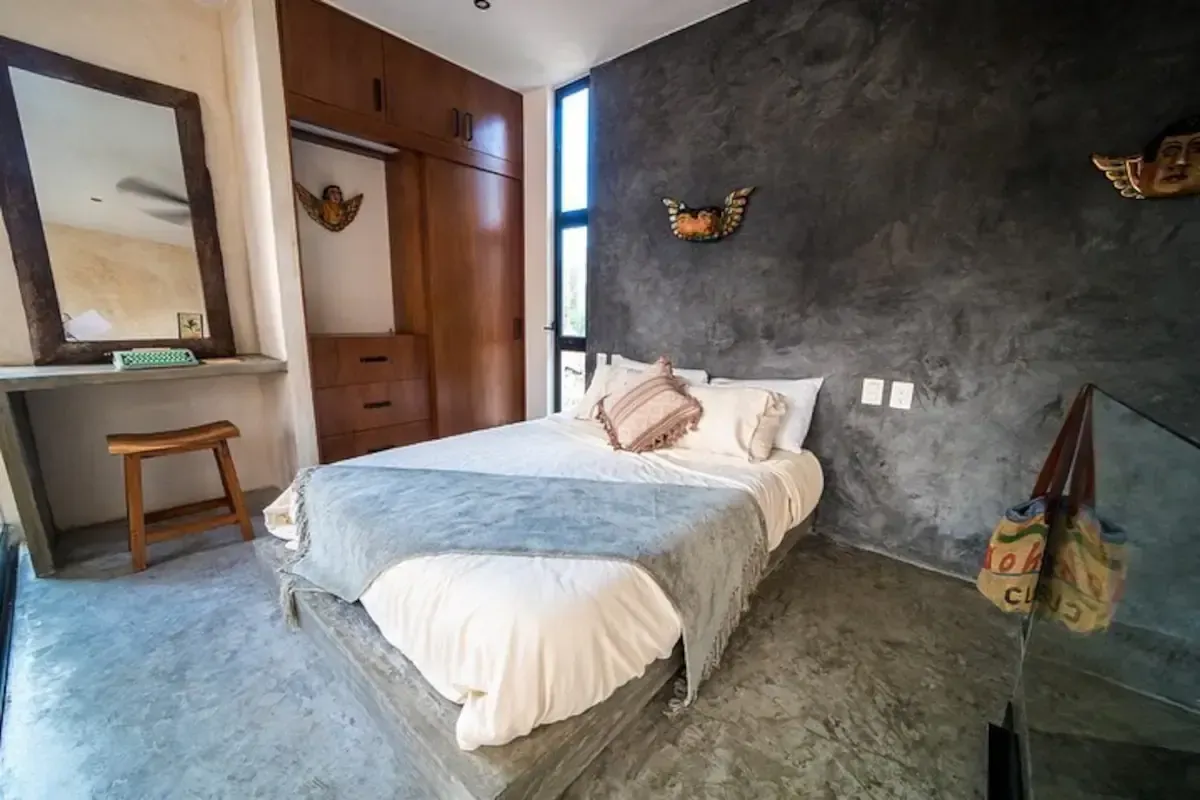 A bedroom with a bed , mirror and dresser.