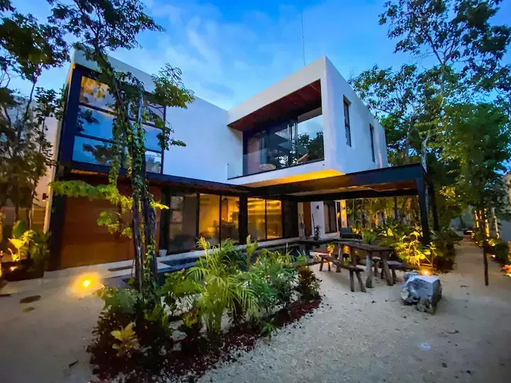 A modern house with a lot of windows and a picnic table in front of it.