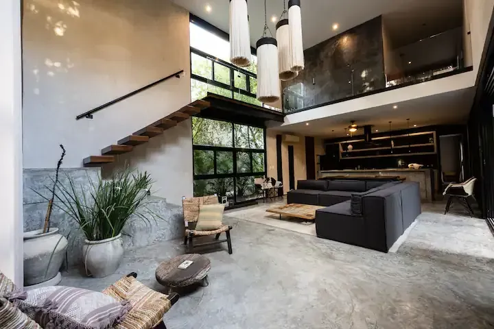 A living room with a couch , chairs , and stairs in a house.