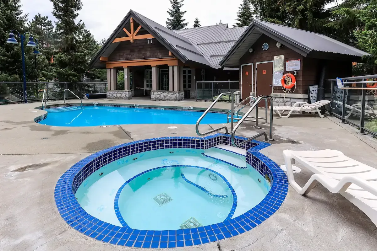 A house with a pool and a hot tub in front of it