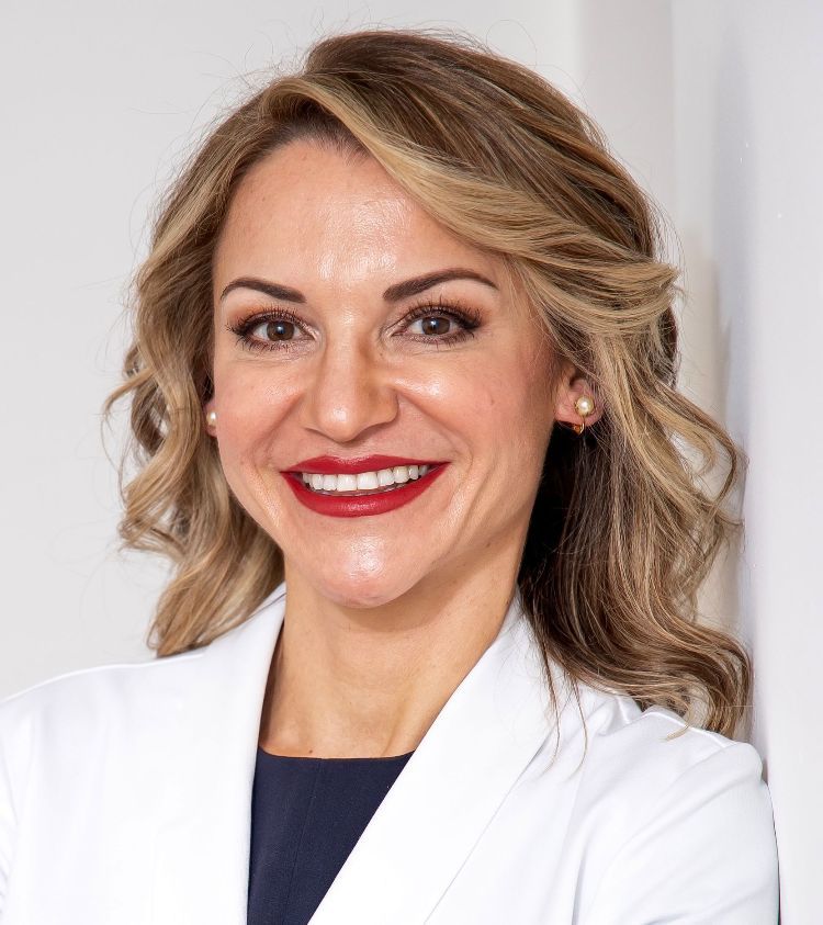 A woman in a white coat is smiling for the camera