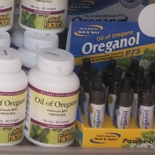 Bottles of oregano oil supplements on a store shelf, displaying various brands and formulations.