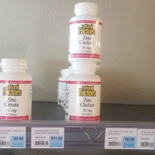 Bottles of Natural Factors zinc supplements on a store shelf, with price tags below.