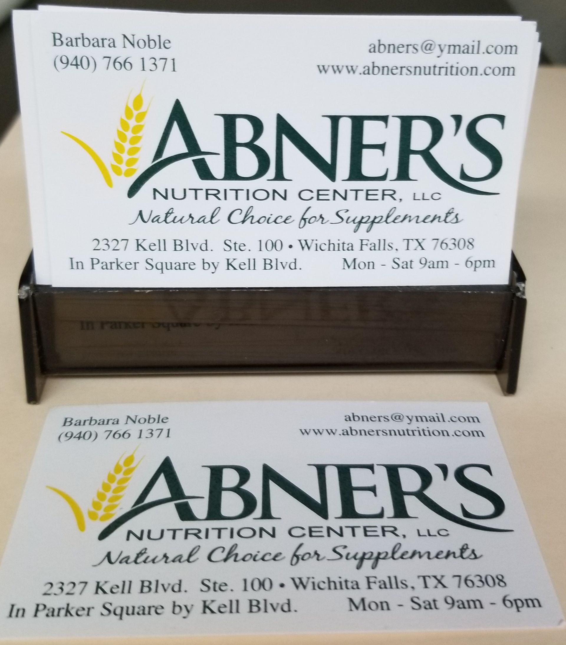 Business cards for Abner's Nutrition Center, with logo and contact info, in a holder.