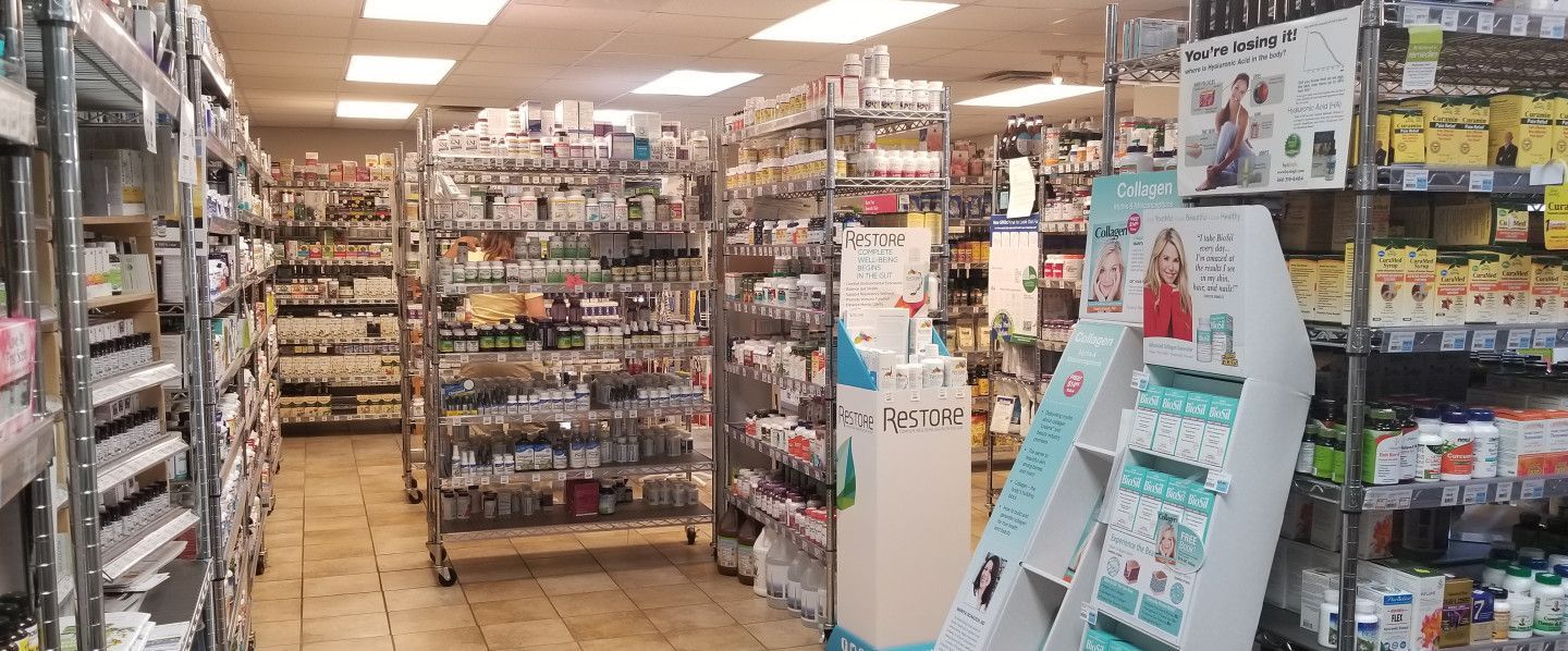 Interior of a store with many shelves of products. Shelves fill the space. Aisle with floor displays is on the right.