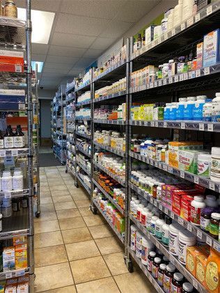 Inside view of a health supplement store, narrow aisle with shelves stocked with various bottles and containers.